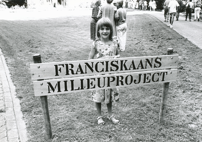 850841 Afbeelding van een meisje achter het bord 'Franciskaans Milieuproject' dat zojuist geplaatst is, als officiële ...